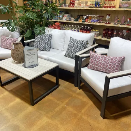 Modern indoor seating group with white cushions, patterned pillows, and a wooden top coffee table in showroom.
