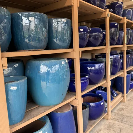 Shelves filled with large glossy blue ceramic pots in various shades and sizes at a garden store