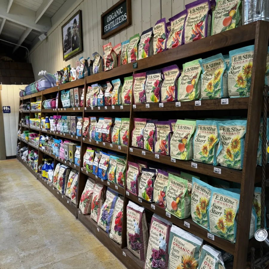 Shelves filled with various bags of E.B. Stone organic fertilizers arranged in a garden store aisle.