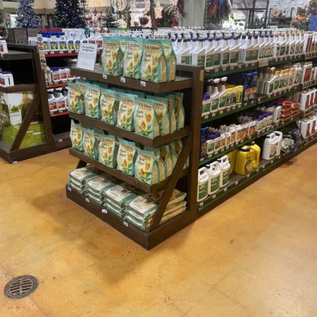 Store display shelves stocked with lawn care products including seed bags and liquid fertilizers in a garden center.