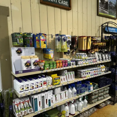 Retail display of indoor plant care products including fertilizers, grow lights, sprays, and soil additives on shelves.