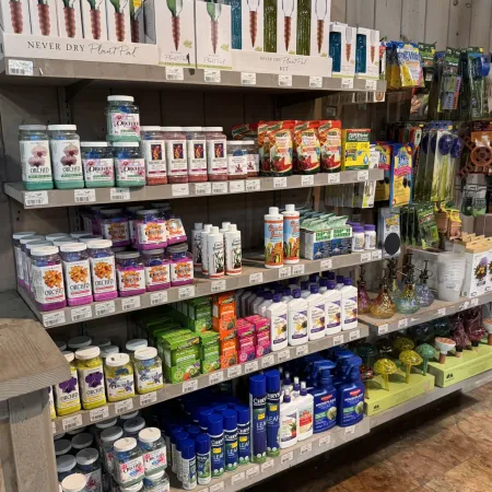 Shelves stocked with various plant care products including fertilizers, orchid food, sprays, and gardening tools.