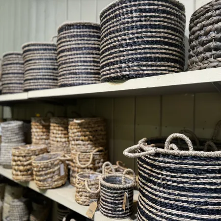 Shelves displaying various sizes of woven storage baskets in natural and dark colors with handles in a store setting