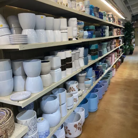 Shelves filled with various ceramic pots and planters in different shapes, sizes, and colors in a store aisle.